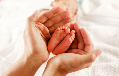 Cropped image of baby hands on bed