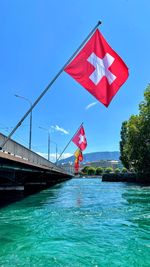 Red flag on river against blue sky