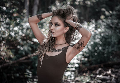 Portrait of woman standing against tree