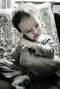 Cute baby girl sitting on sofa at home