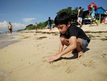 Full length of boy playing with sand at beach