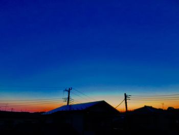 Low angle view of silhouette buildings against blue sky