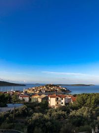 Buildings by sea against blue sky