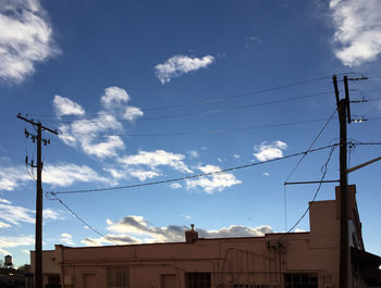 Low angle view of electricity pylon against cloudy sky
