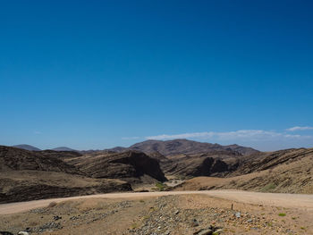 Scenic view of arid landscape against clear blue sky