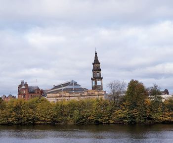 View of building by river against cloudy sky