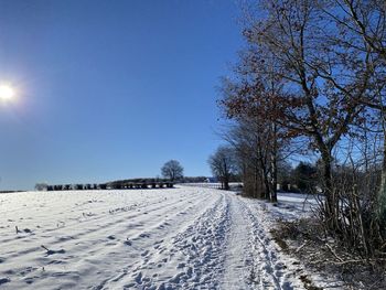 Snow covered land against clear blue sky