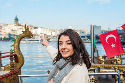 Portrait of smiling young woman against buildings in city