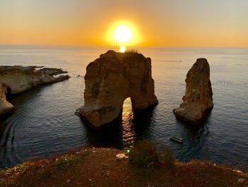 Rock formation on sea against sky during sunset