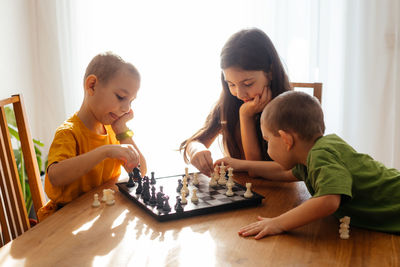 Siblings playing chess at home