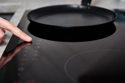 Woman hand turns on modern induction stove in the kitchen