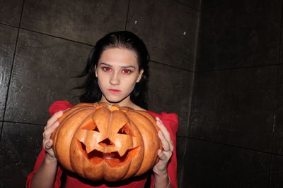 Portrait of young woman with pumpkin on floor
