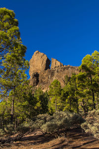 Low angle view of rocky mountain against blue sky