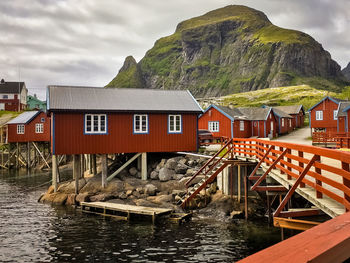 Stilt houses by river against mountains