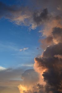 Low angle view of sunlight streaming through clouds during sunset