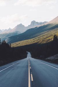 Road leading towards mountains against sky