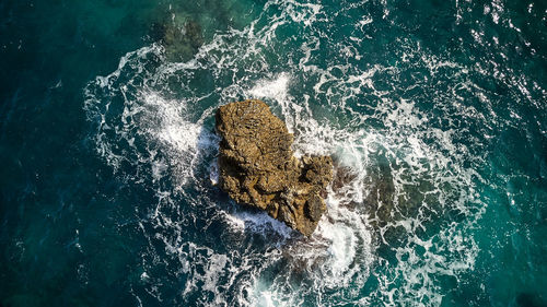 High angle view of sea waves splashing on rock