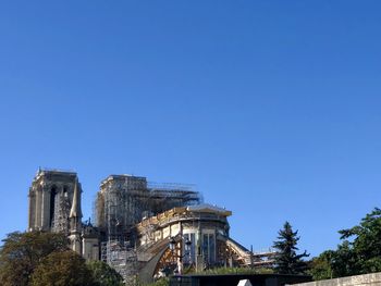 Low angle view of burned notre dame against blue sky in paris