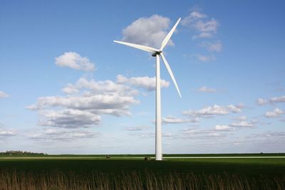 Wind turbines on field against sky