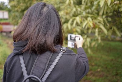 Rear view of woman photographing in park