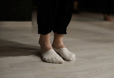 Low section of man wearing socks while standing on hardwood floor