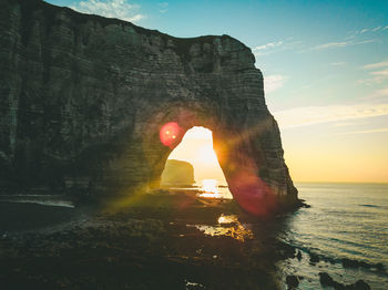 Rock formation in sea against sky during sunset