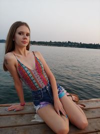 Portrait of woman sitting against lake