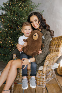 Portrait of a happy mother with her four-year-old son, who is sitting on her lap in a wicker chair