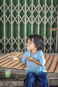 Boy looking away while sitting on fence