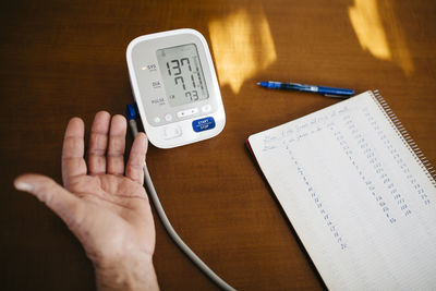 Hand of senior man controlling his blood pressure, close-up