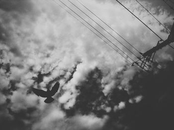 Low angle view of silhouette power lines against sky