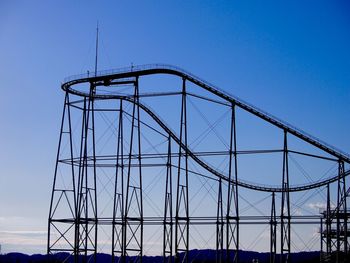 Low angle view of ferris wheel against clear blue sky