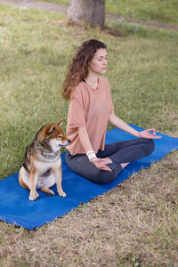 Portrait of young woman with dog on field