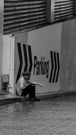 Man sitting on wall of building