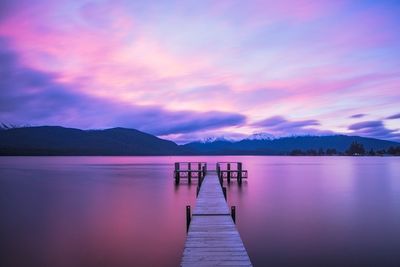 Pier over lake against sky during sunset