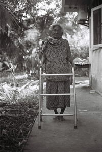 Full length of senior woman walking with walker on footpath