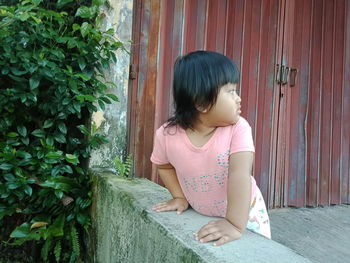 Girl looking away while sitting on pink face