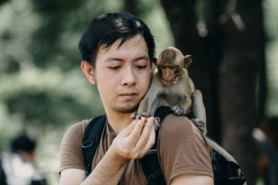Monkey taking food from man while sitting on his shoulder