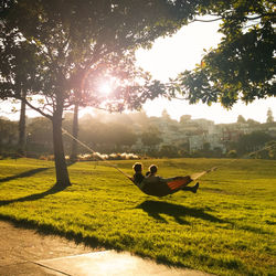 Rear view of men relaxing on hammock at park