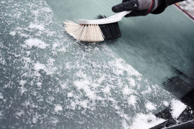 Person brushing snow on windshield