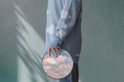 A man with a mirror in his hands reflecting the sky