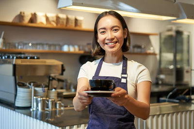 Portrait of young woman using mobile phone in cafe