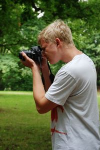 Side view of man holding camera on field