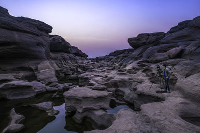 Man photographing of rock formations against sky