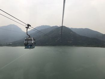 Overhead cable car over mountains against sky