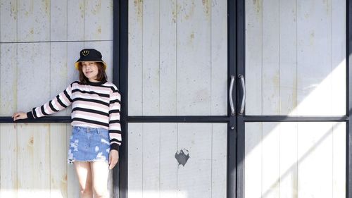 Portrait of young woman standing against wall