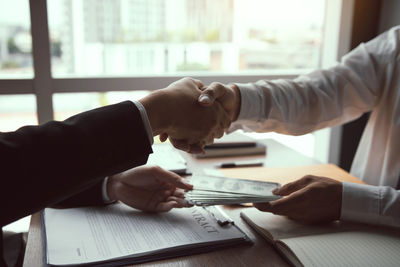 Midsection of couple holding hands on table