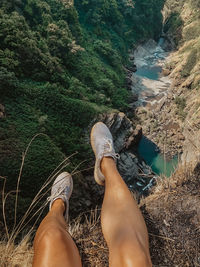 Low section of woman sitting on cliff