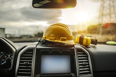 Close-up of hardhat on dashboard in car against sky