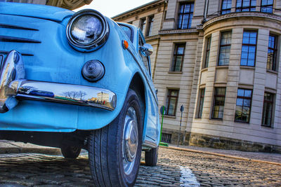 Low angle view of blue vintage car parked on road in city